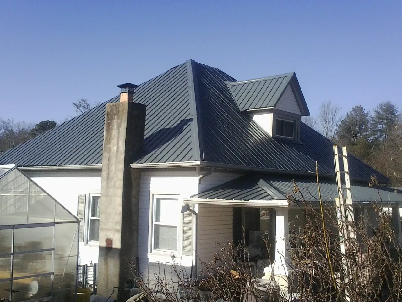 Dark blue standing seam metal roof on a white farmhouse with dormer — Slate & Tile Roof Repair by Roofing Brothers in Pe Ell