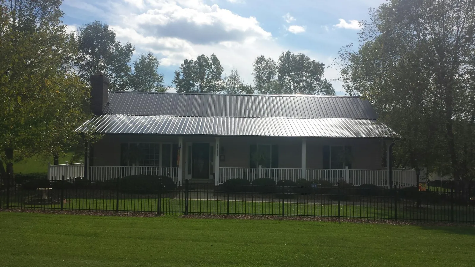 Gray metal roof on a brick ranch with a full width front porch — Gutter Guard Installation work by our crew in Pe Ell