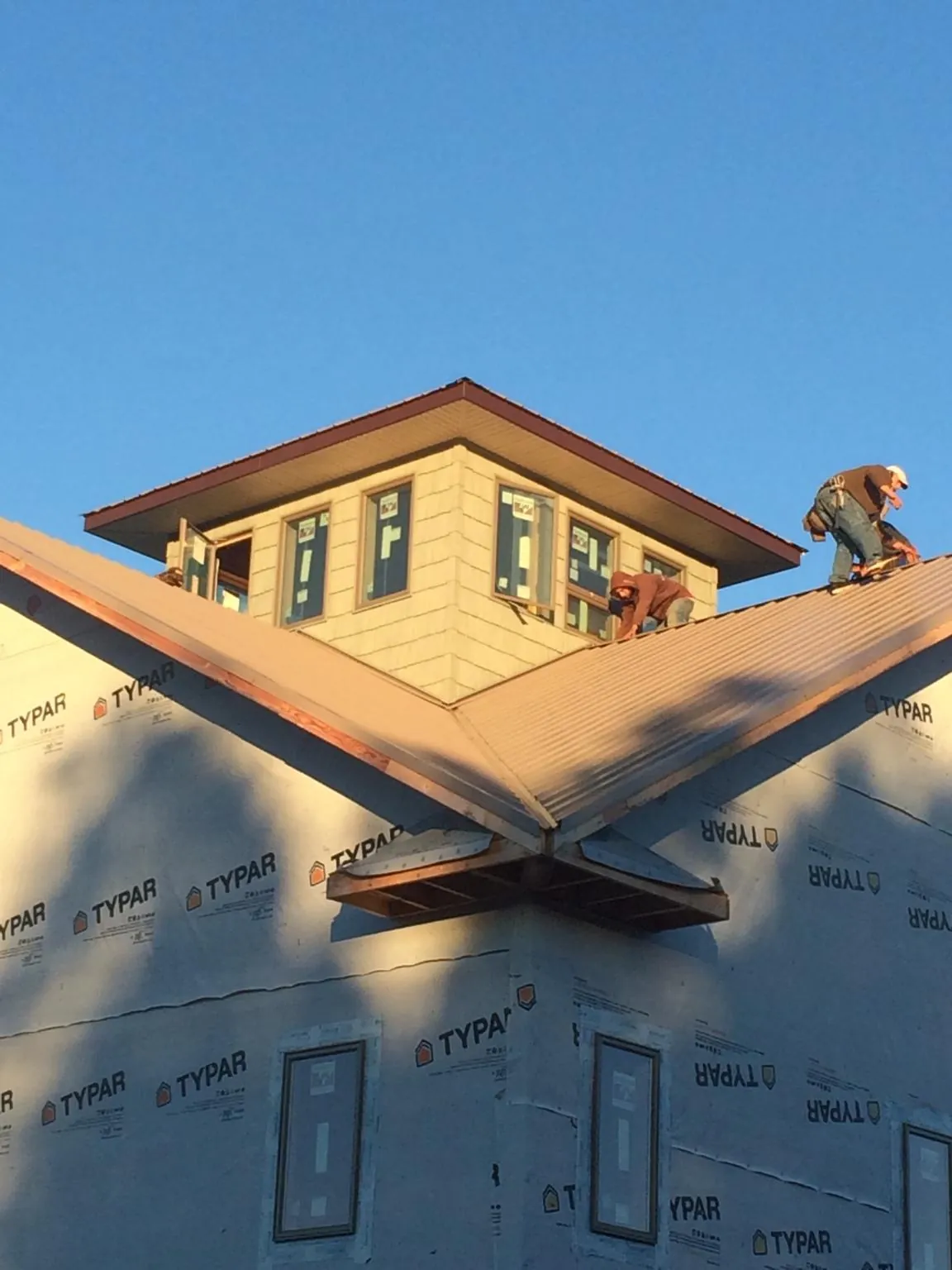 Roofers working around a rooftop cupola on a new metal roof at sunset — Roof Waterproofing in Pe Ell by Roofing Brothers